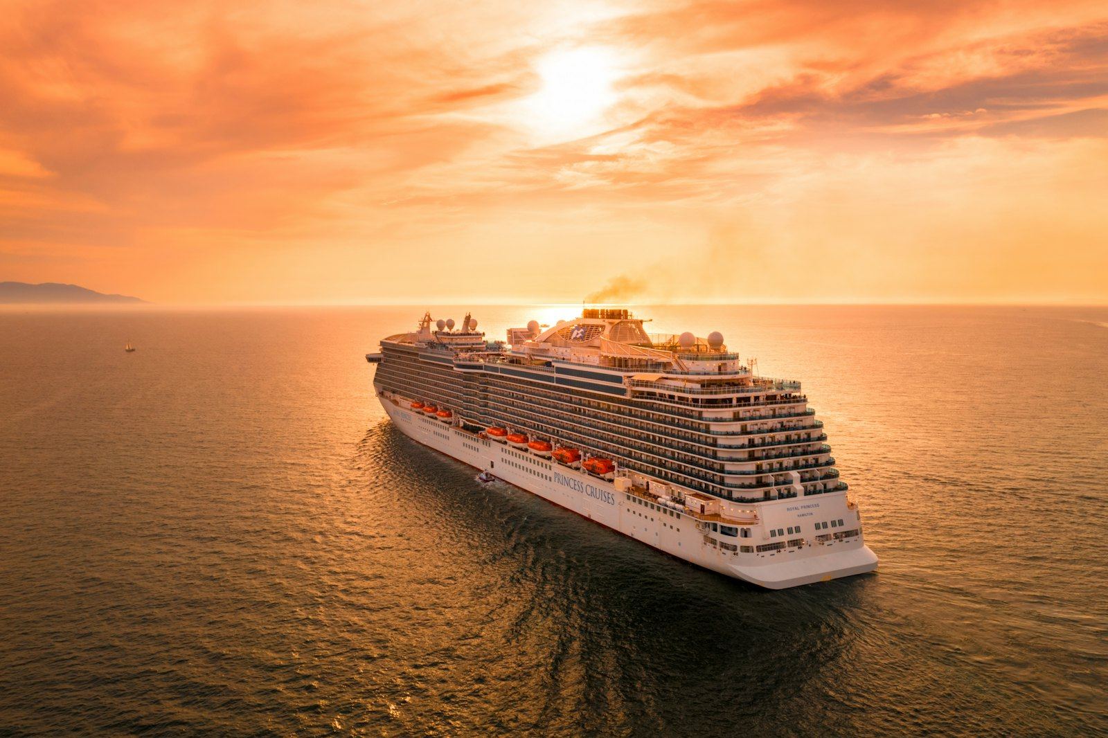 Cruise ship sailing into a golden sunset at sea